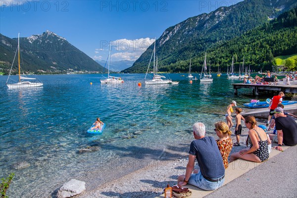 Holidaymakers on the lake promenade with sailing boats