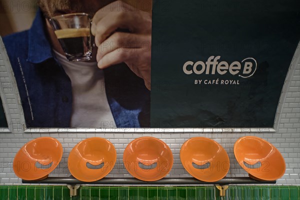 Orange seats in front of a large poster in the metro