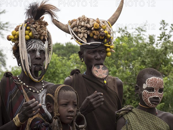 Women and children of the Mursi tribe with headdress and lip plate