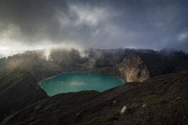 Fog over crater with turquoise crater lake