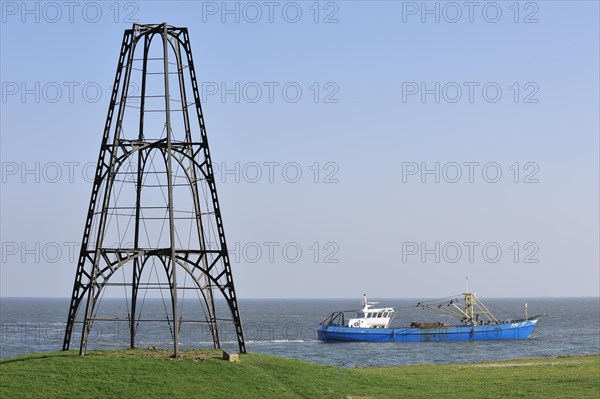 Cast iron beacon from 1854 and fishing boat sailing the Wadden Sea