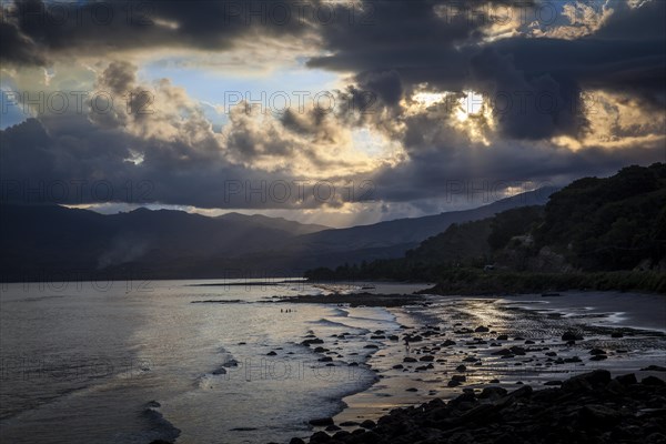 Sunset on coast with rocks and mountains