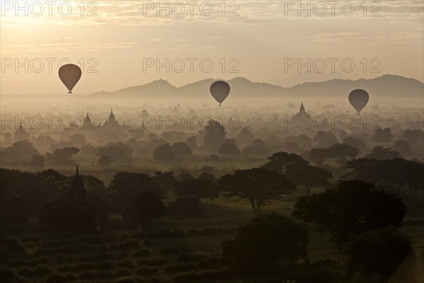 Hot air balloons over landscape with stupas