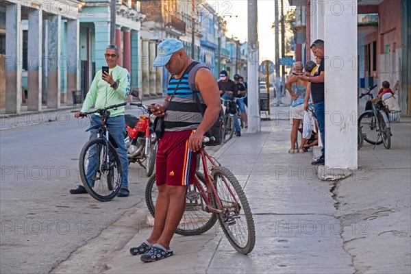 Group of local Cuban inhabitants trying to connect smartphones to the internet via Wi-Fi in the streets of Colon