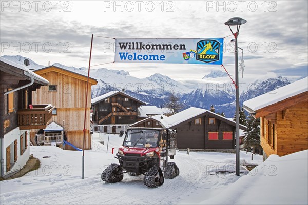 Polaris Taxi Walker XP fitted with rubber tracks driving through the Swiss traffic-free village Riederalp in the snow in winter