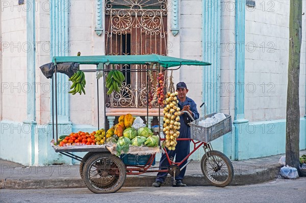 Cuban street vendor selling fruit and vegetables from mobile food stand on tricycle in the city Camagueey on the island Cuba