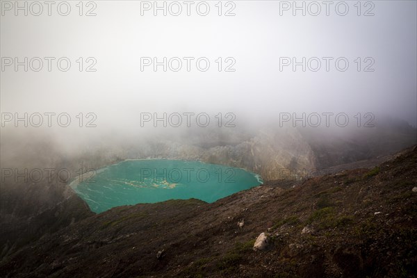 Fog over crater with turquoise crater lake