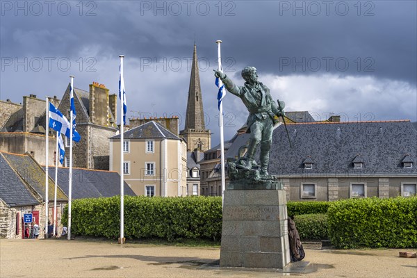 Statue of the privateer Robert Surcouf in front of the old town with the tower of St Vincent Cathedral