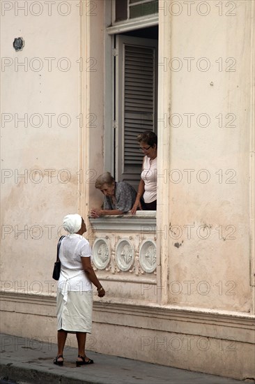 Elderly Cuban women in window talking to black Afro-Cuban woman in Santiago de Cuba