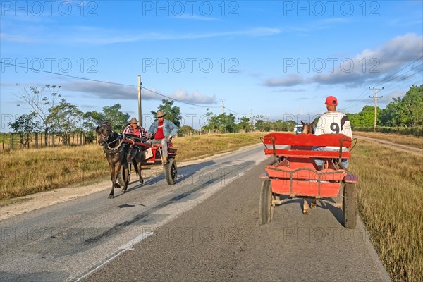 Cubans riding horse-drawn cart and carriage along the Carretera Central