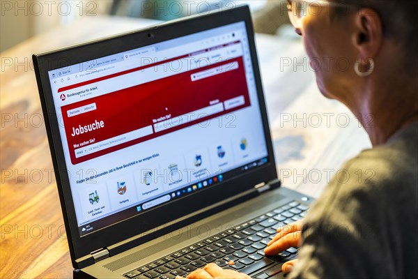 Woman with glasses looking for a job sits at home in front of her notebook and checks the internet site of the Federal Employment Agency for job offers