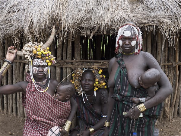 Women with small children in front of a hut