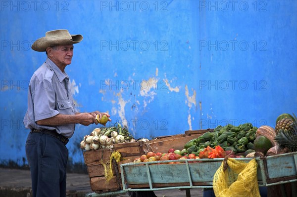 Cuban vendor selling fresh fruit and vegetables at market stall in Vinales