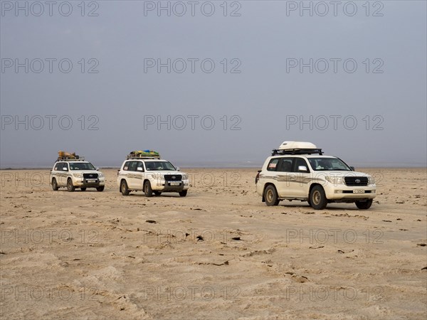 Tourists in off-road vehicles driving on salt desert