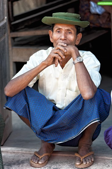 Man squatting in front of his house