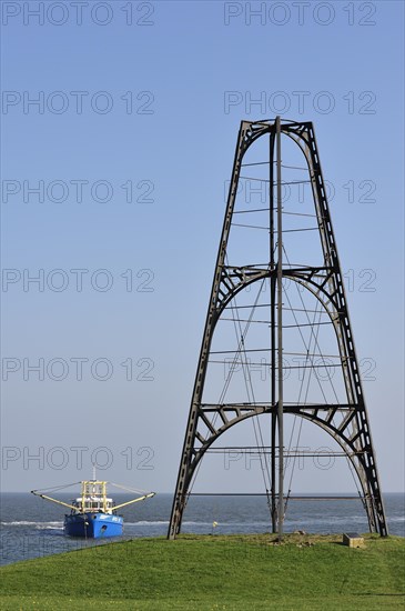 Cast iron beacon from 1854 and fishing boat sailing the Wadden Sea