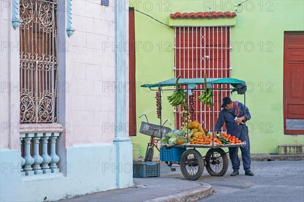Cuban street vendor selling fruit and vegetables from mobile food stand on tricycle in the city Camagueey on the island Cuba