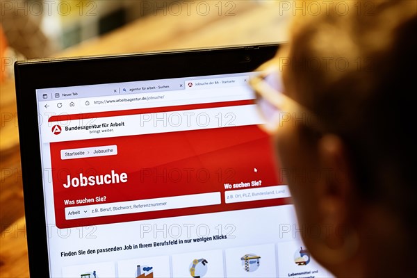 Woman with glasses looking for a job sits at home in front of her notebook and checks the internet site of the Federal Employment Agency for job offers