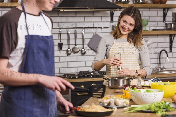 Smiling couple cooking dishes together