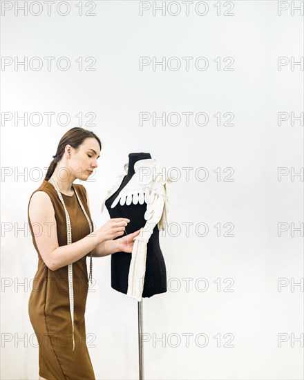 Young female designer sewing dress shop