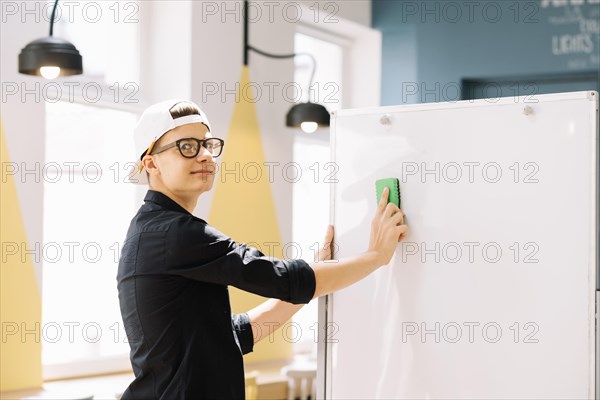 Expressive schoolboy cleaning blackboard