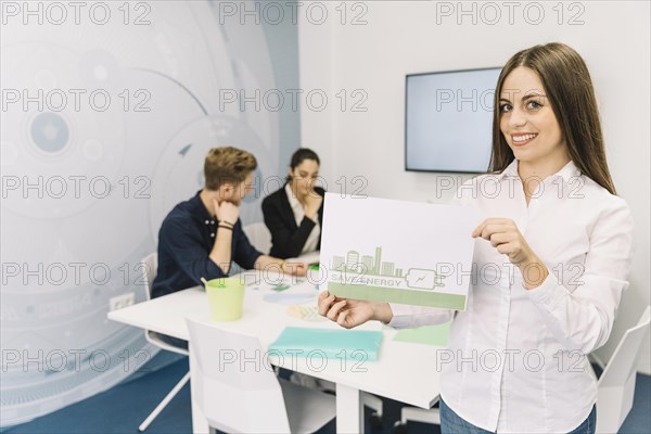 Smiling young businesswoman showing energy saving concept office