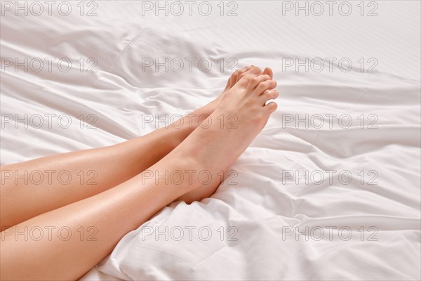 Female feet with soft skin on white linen