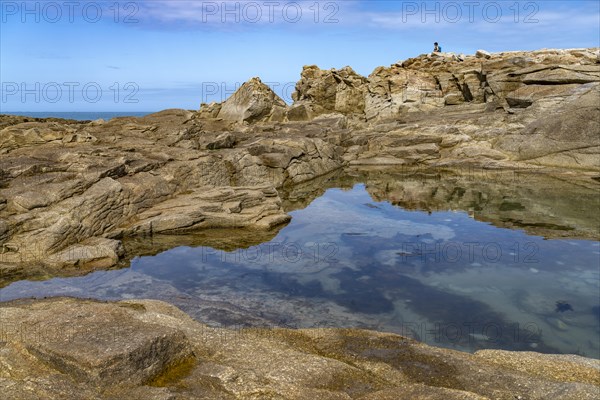 Natural pool among the rocks of the pink granite coast Cote de Granit Rose on the island Ile Grande