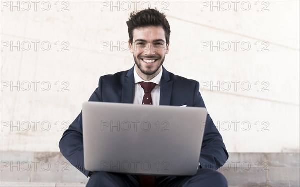 Front view man with laptop looking camera