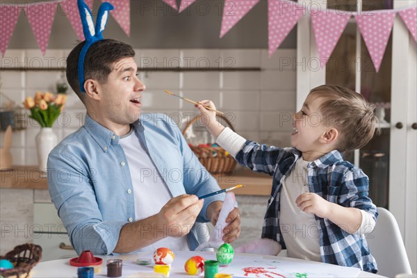 Adorable little boy trying paint his father