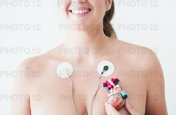 Female with electrocardiogram leads hand with figurine heart