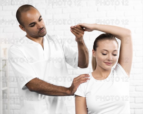 Male physiotherapist checking woman s arm flexibility