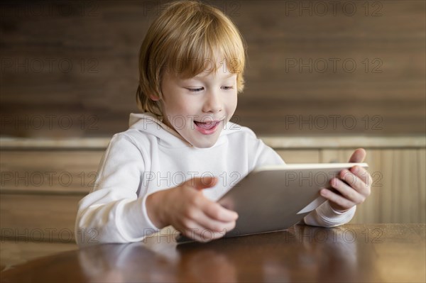 Front view young boy using tablet table