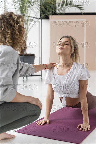 Teacher helping woman with pose