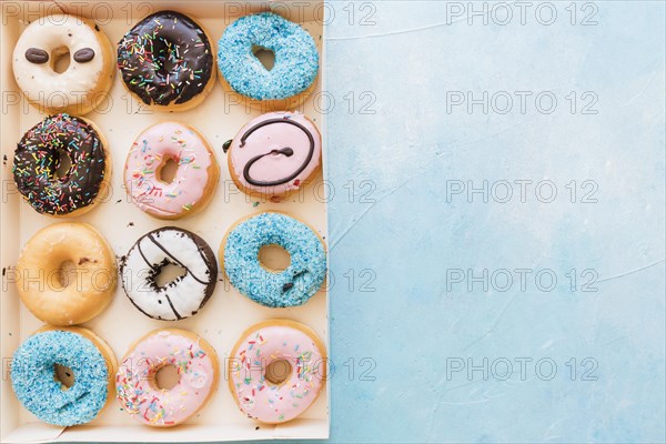 High angle view multi colored fresh donuts box blue background