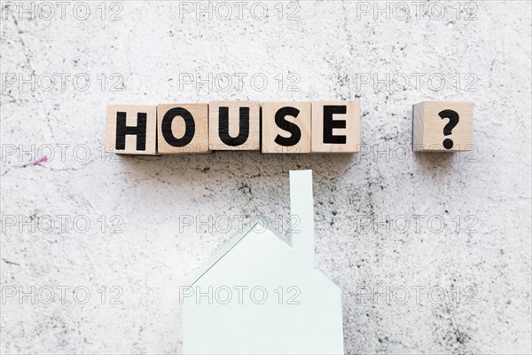 Arranged house text blocks with question sign paper house model against concrete backdrop