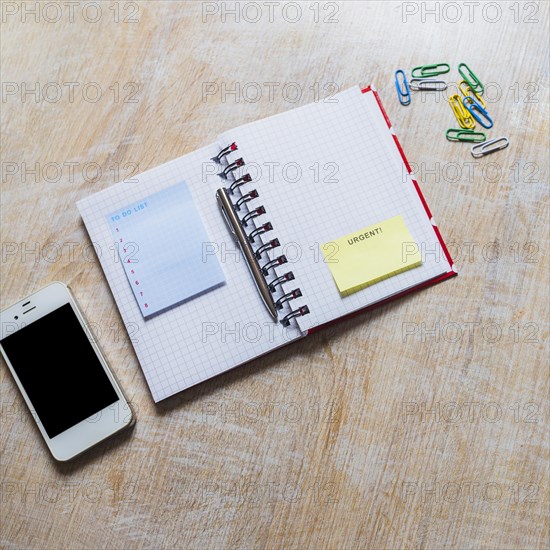 List notepad urgent sticky note checkered notebook with smartphone paperclip