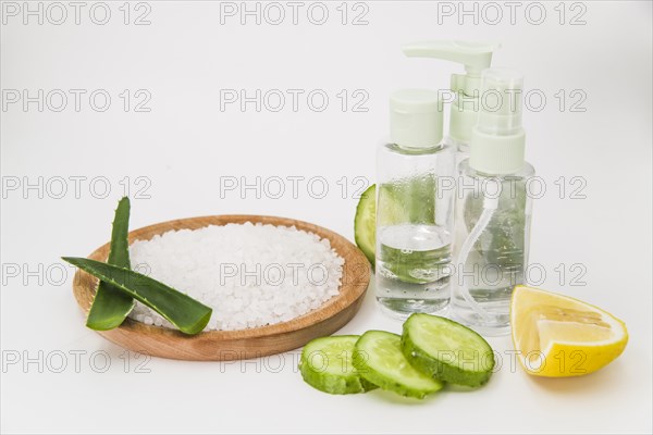 Rock salt wooden plate cucumber slices lemon spray bottle white backdrop