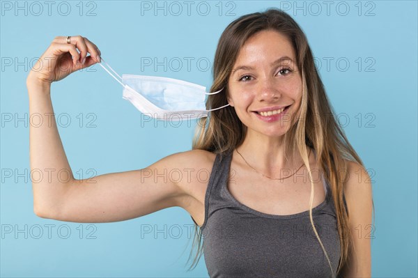 Blonde woman taking off her medical mask