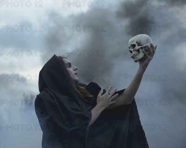 Man holding skull dark looking it