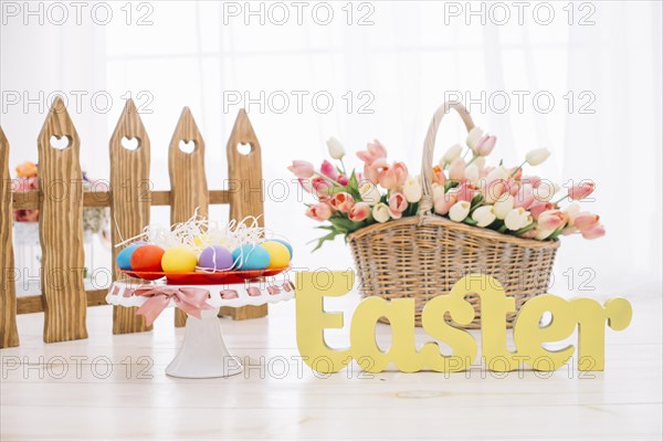 Colorful easter eggs tulips basket with yellow easter text wooden desk