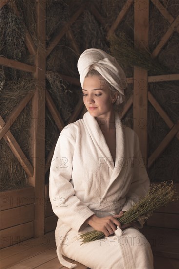 Smiling beautiful young woman sitting bench sauna