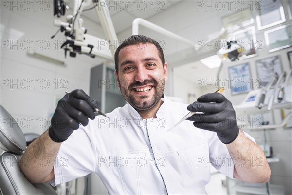 Portrait smiling male dentist with dental tools