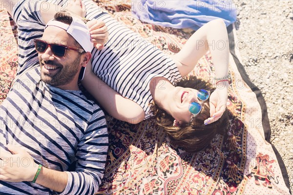 Smiling young couple wearing sunglasses lying blanket