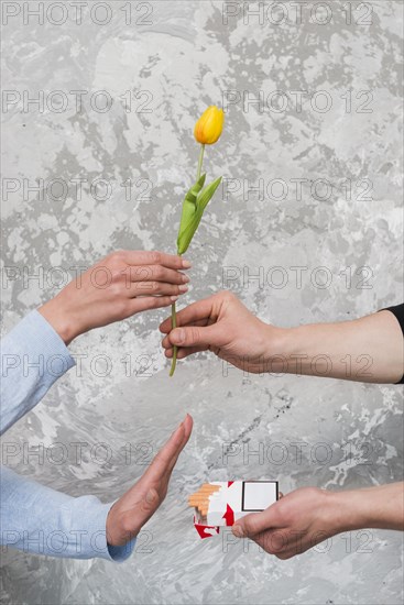 Woman s hand accepting yellow tulip rejecting pocket cigarette from man