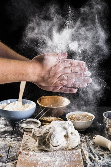 Close up baker s hand dusting flour dough with ingredients table