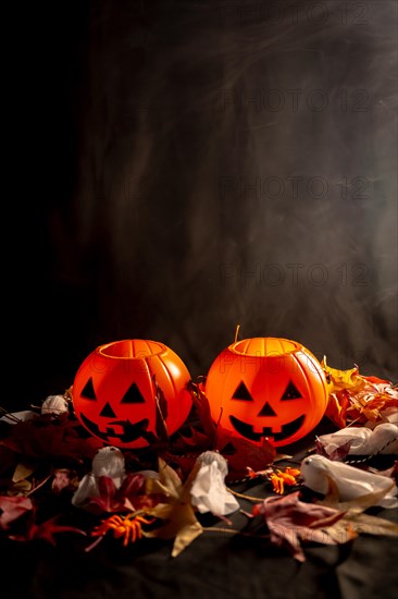 Halloween pumpkins on autumn leaves with smoke on a black background