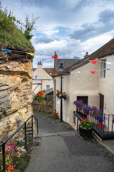 Alley decorated with flowers and colourful flags in the fishing village of Pittenweem