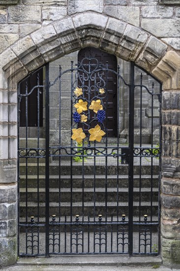 Ironwork in the form of golden vine leaves and vines on a wrought iron door