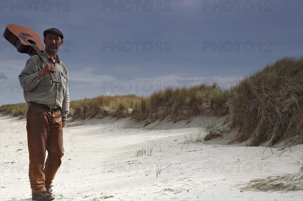 Man with guitar in the dunes